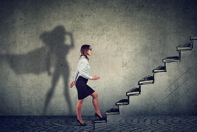 business woman climbing stairs with superhero shadow