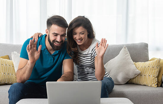 happy couple holding up hands looking at computer screen